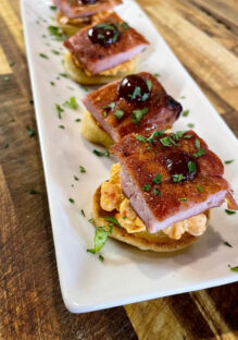 A close-up view of smoke pork blinis served with pimento cheese