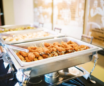A buffet setup with 3 chafing dishes with the focus on coconut chicken satay