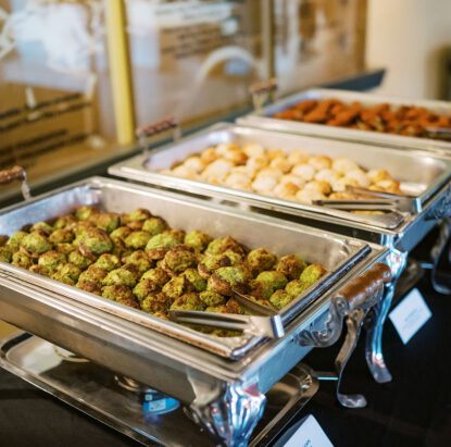 A buffet with 3 chafing dishes with the focus on spinach and artichoke stuffed mushroom caps {{brizy_dc_image_alt imageSrc=